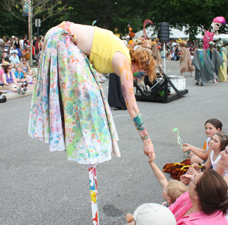 Girl on stilts shakes hands