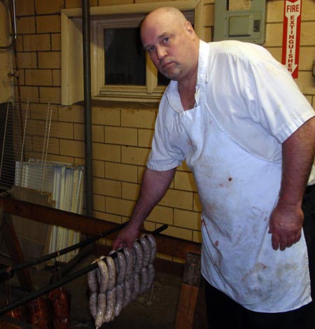 Ed Jesse of Old World Meats hangs sausage to get ready for the smokeshop