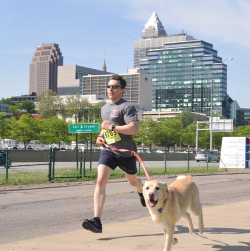 Lt. Timothy Jones, a member of Coast Guard Marine Safety Unit Cleveland, runs with Sam, a golden retriever