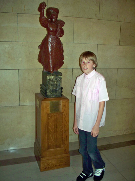 Boy poses by the Slovenian Lady statue wood carving in Cleveland City Hall
