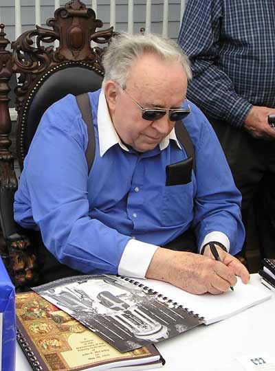 Father Mac signs another copy of his book